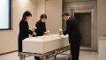 白い棺を前に少人数の家族が静かに故人を見送る様子