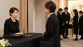 葬儀会場の受付で喪服の女性に対応する受付係